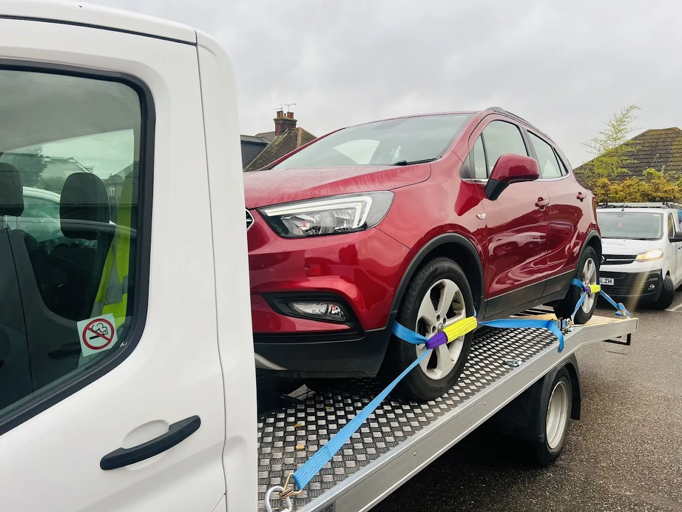 Professional flatbed car recovery truck loading red vehicle - UK breakdown service